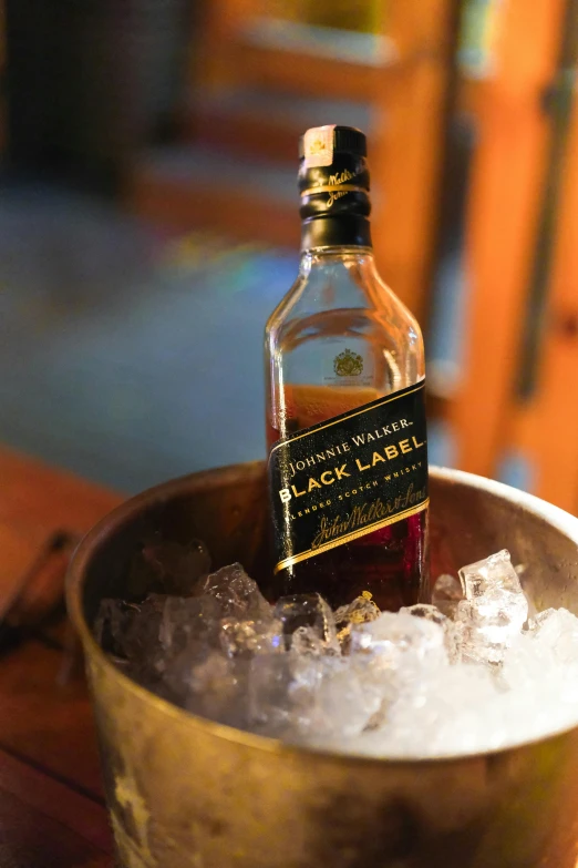 the bottle of whiskey has been in a small metal bowl with ice