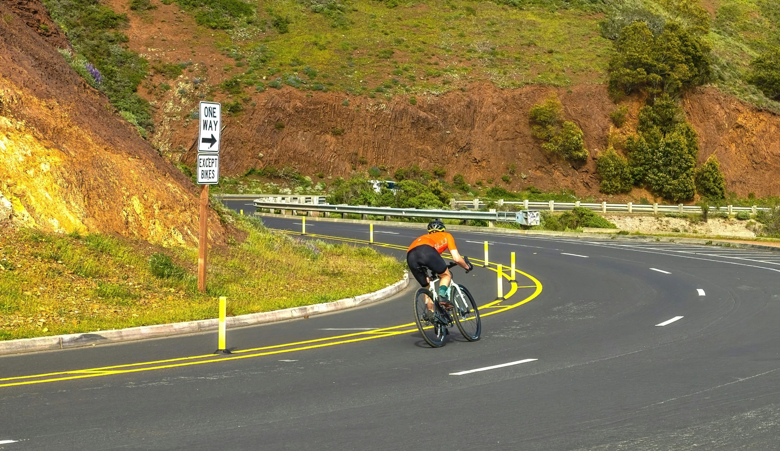 two people riding bicycles on a mountain side road