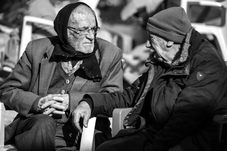 an old man sitting next to another old man