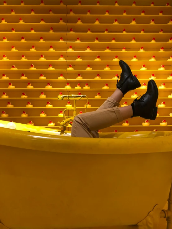 a woman laying down in the bathtub with yellow walls