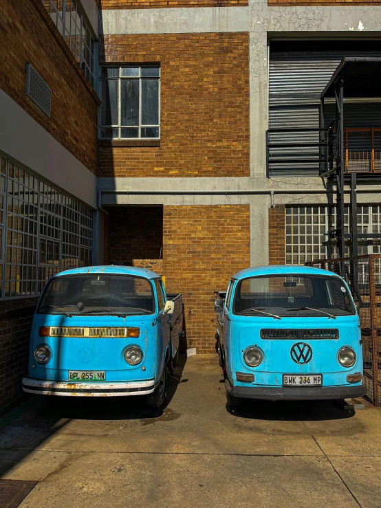 two blue cars sitting side by side next to an apartment building