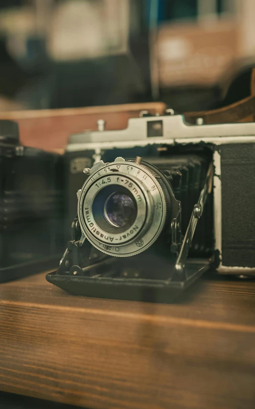 an old style camera sitting on a table next to another old fashioned camera