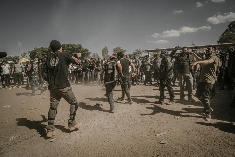 a crowd of people are standing around on dirt