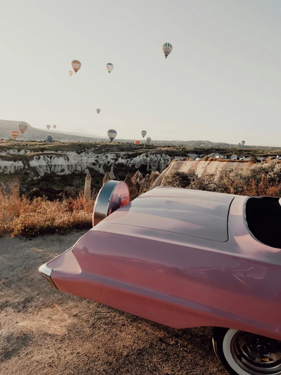 a car parked next to a large group of  air balloons