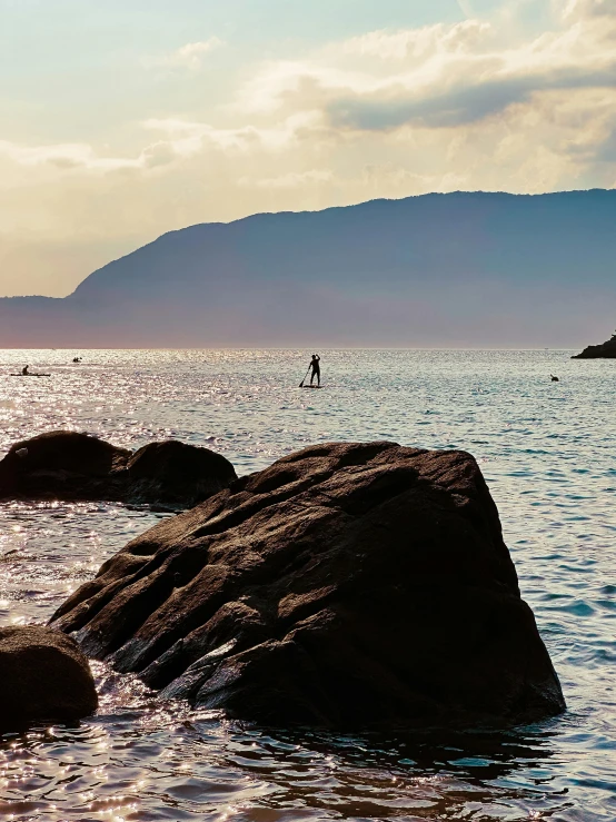 person paddleboarding on the water near large rocks