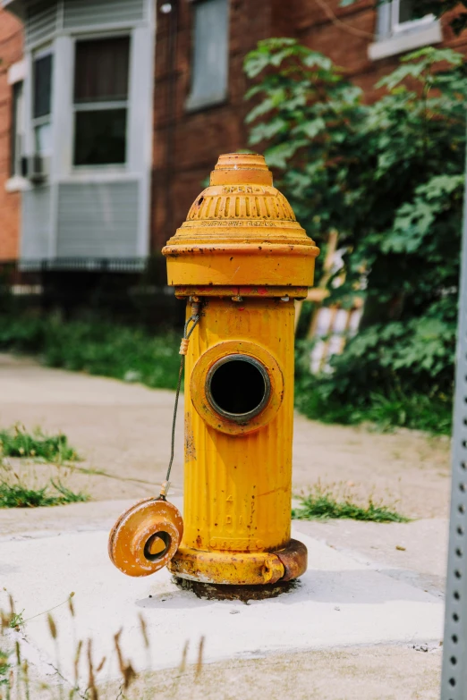 an old yellow fire hydrant sits on the side of a street