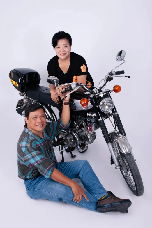 a man sitting next to a motorcycle on a white background