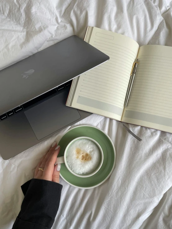 a desk with an open laptop, a mug of coffee, and a notebook