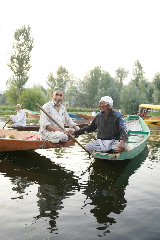 two men paddling canoes in the middle of a body of water