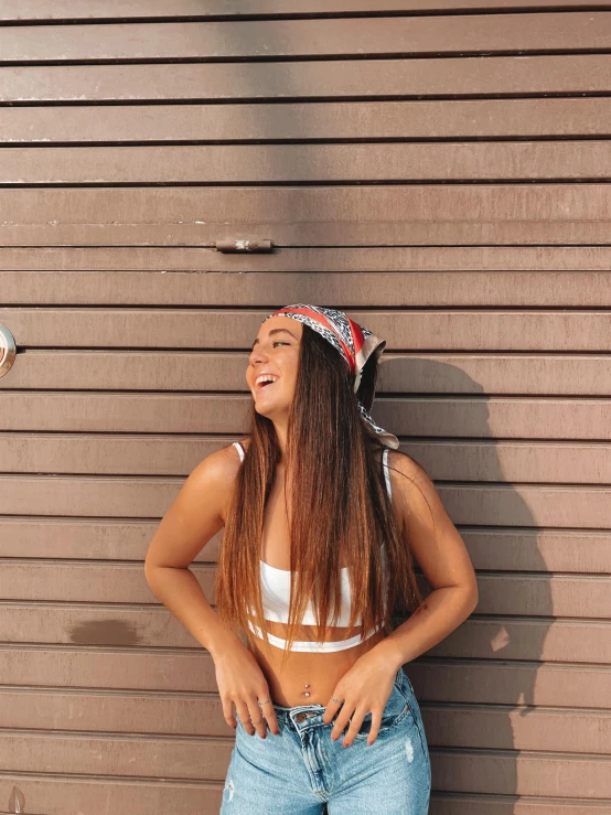 a smiling woman in a bikini top leaning against the wall