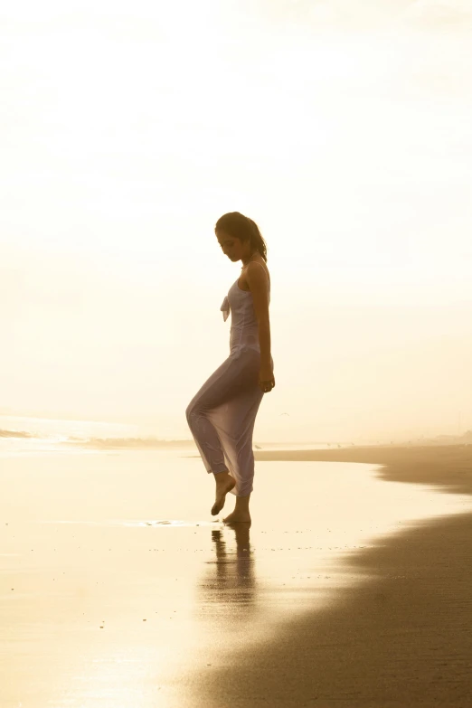 a woman in white dancing on the beach