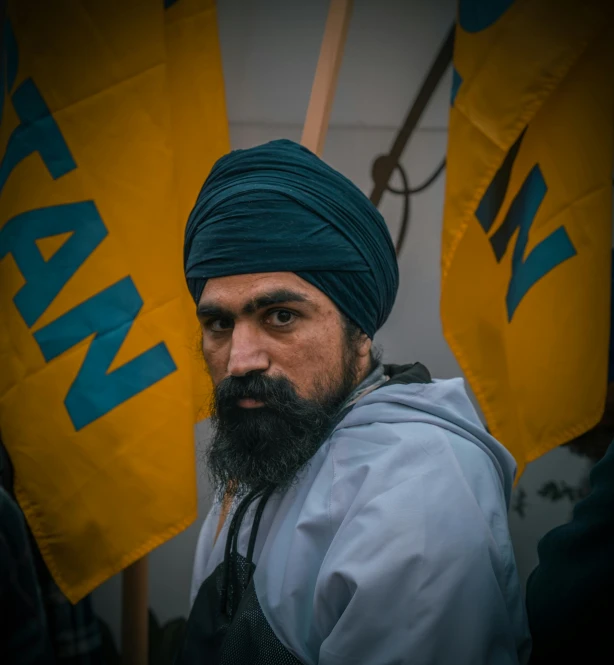 a man in a turban and beard standing next to flags
