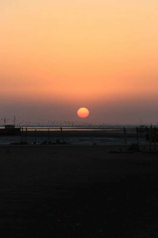 sunset over the ocean with boats in the distance