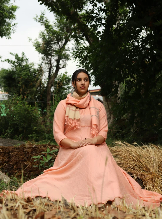 a young woman sitting on top of a pile of dry grass