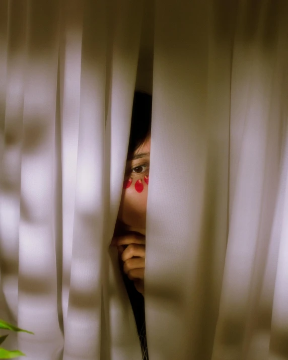 a woman is peeking through a white curtain