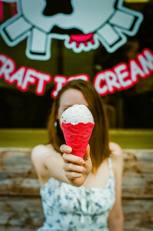girl holding up an ice cream cone with a strawberry cream