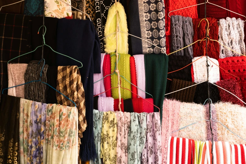 various colored shawls are hanging next to each other