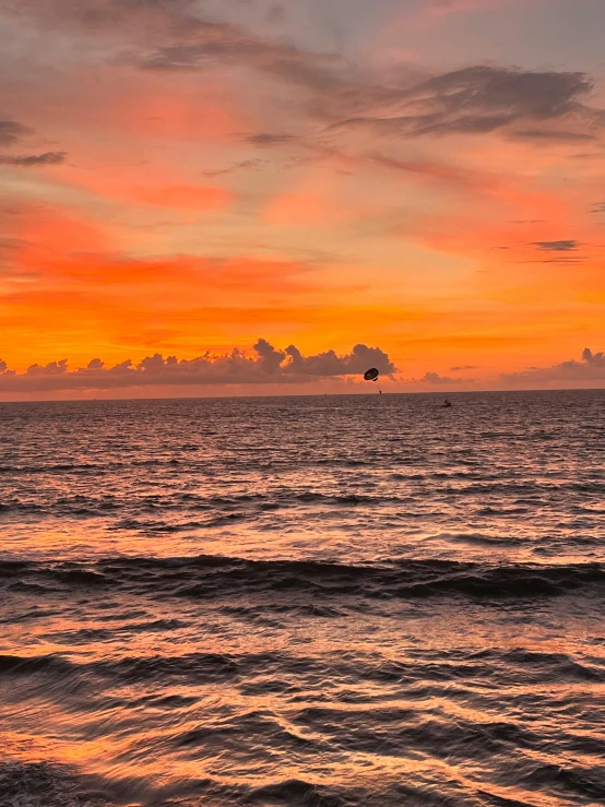 a boat floating in the ocean during a beautiful sunset