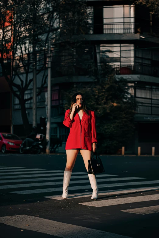 a woman in red poses for a picture while she stands on the crosswalk