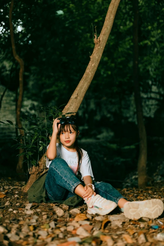 a child sitting on the ground in a wooded area