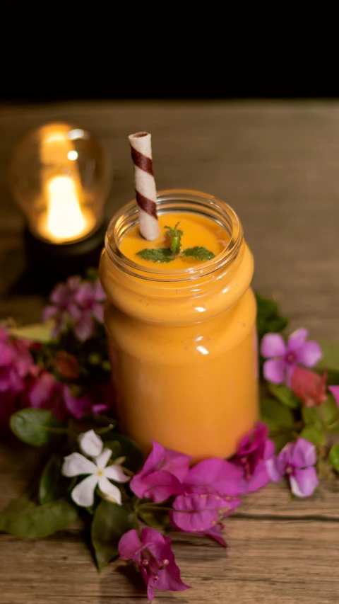 a glass full of juice and with a straw in it sitting on top of some flowers