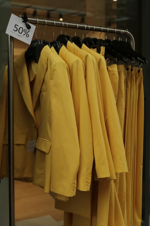 a rack full of yellow coats sitting in a store