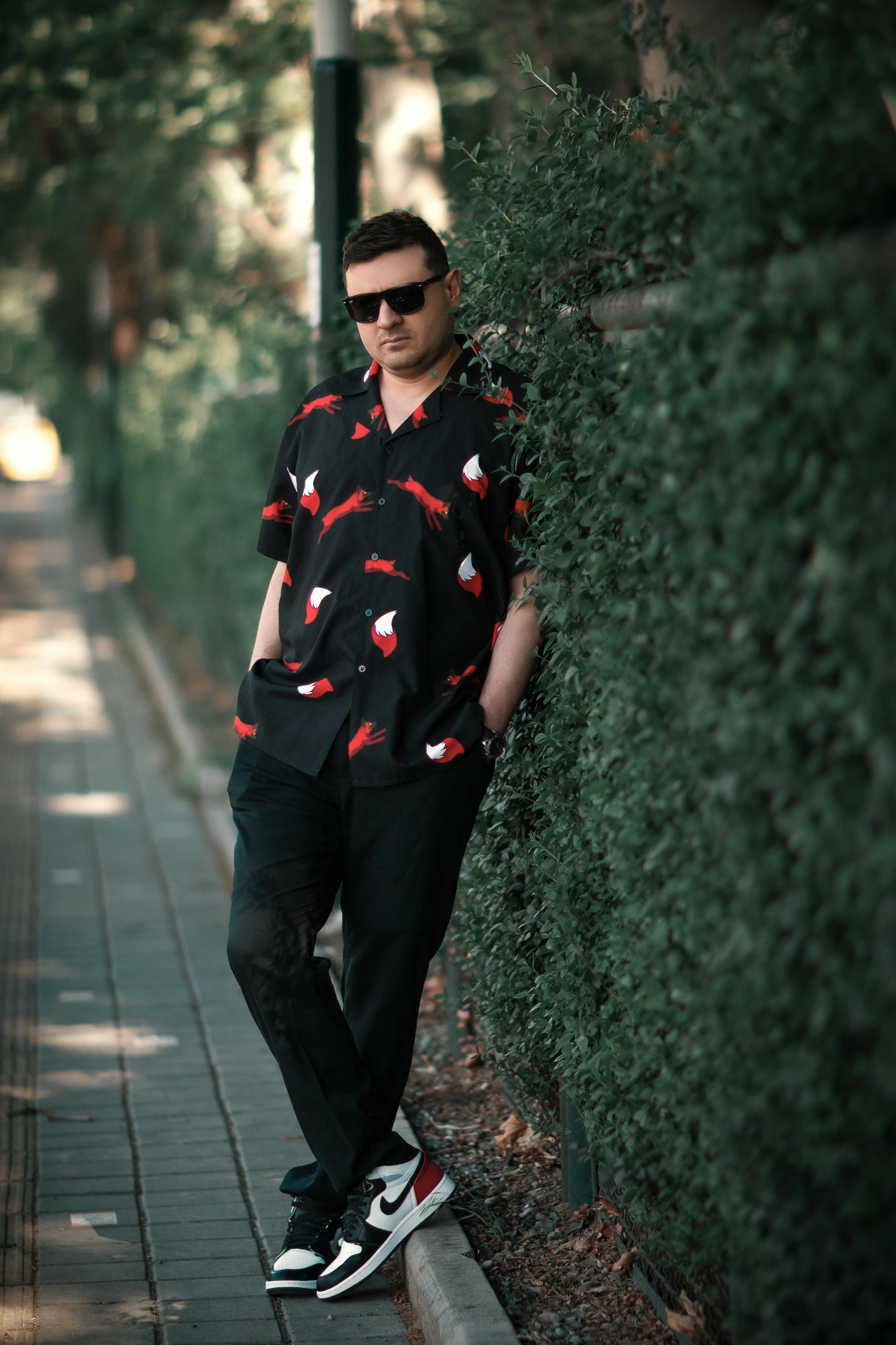 a man standing by a bush next to a street