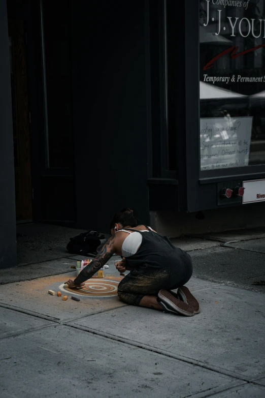 a person kneeling down painting a sidewalk