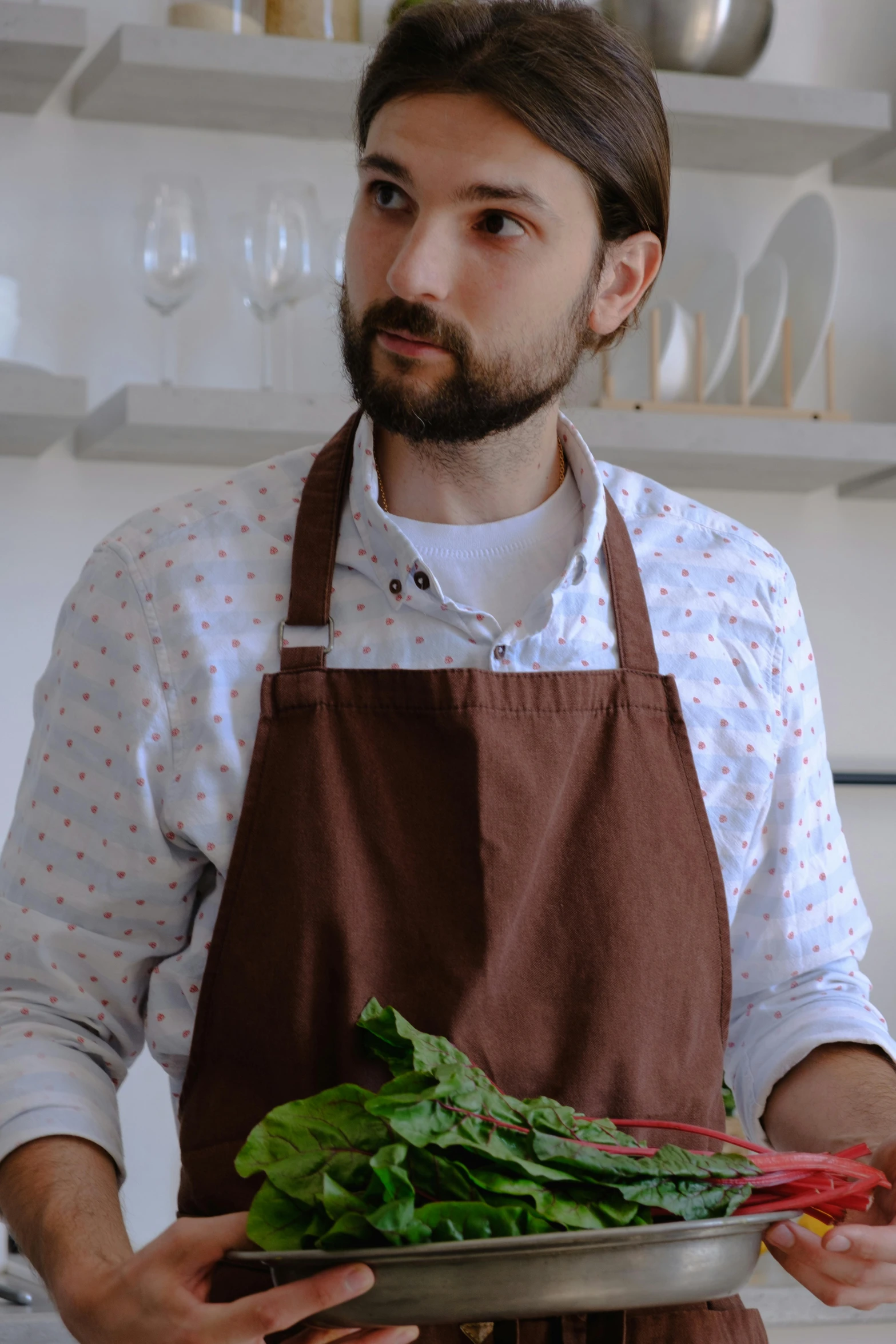 man with apron holding bowl full of greens