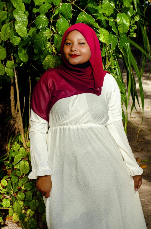 an overweight woman in dress standing near green leaves