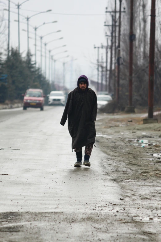 a person with a hat walking down a wet road