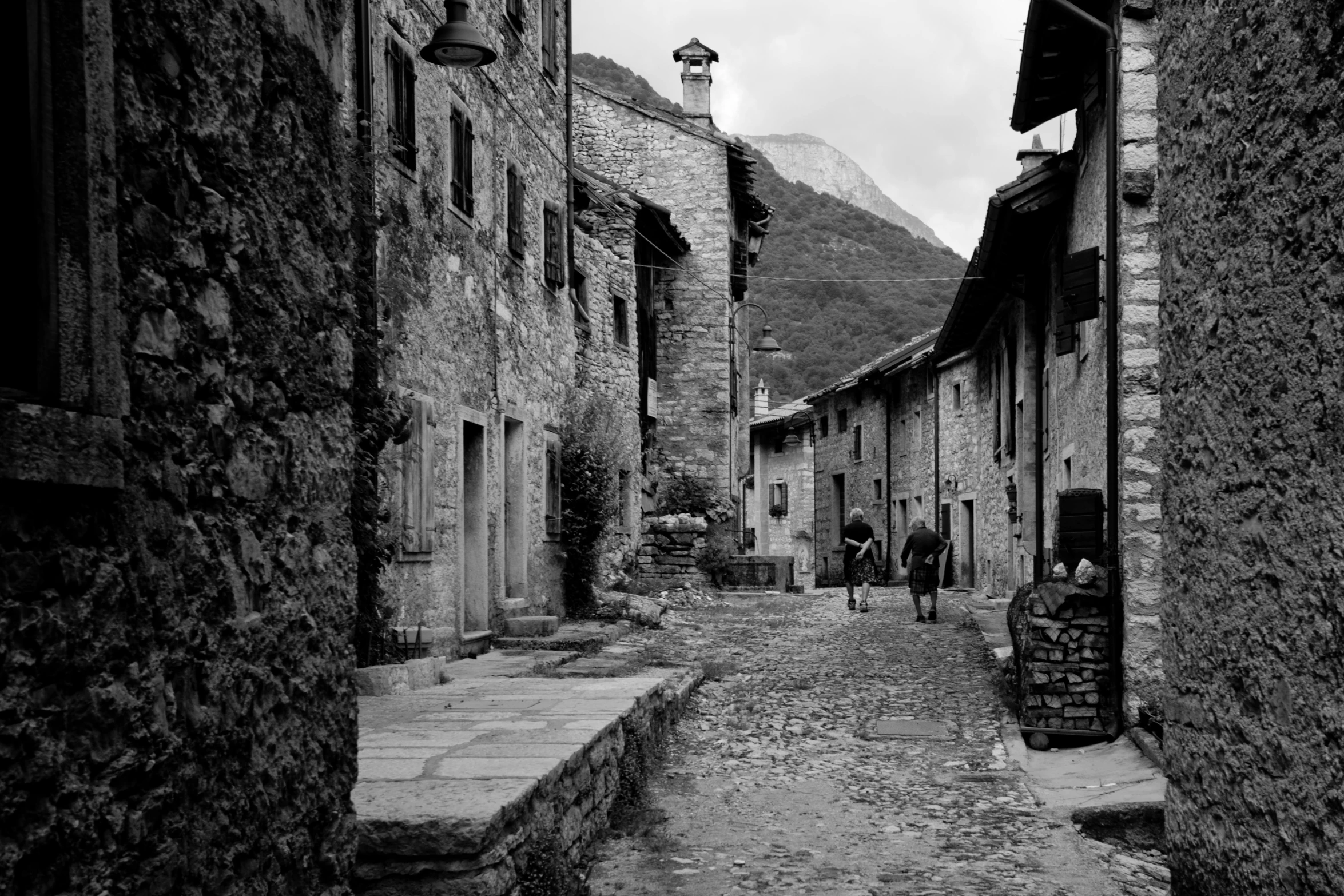 an empty alley in the mountains with people walking