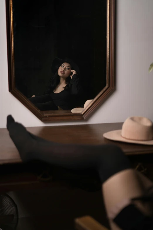 a woman in black dress wearing stockings and heels next to a mirror with her feet on the table