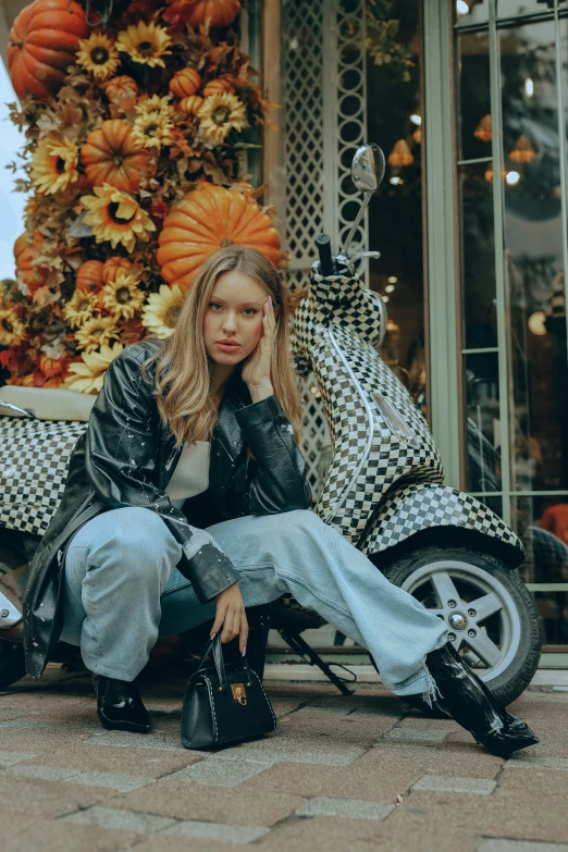 a woman is sitting down next to a motorcycle and pumpkins