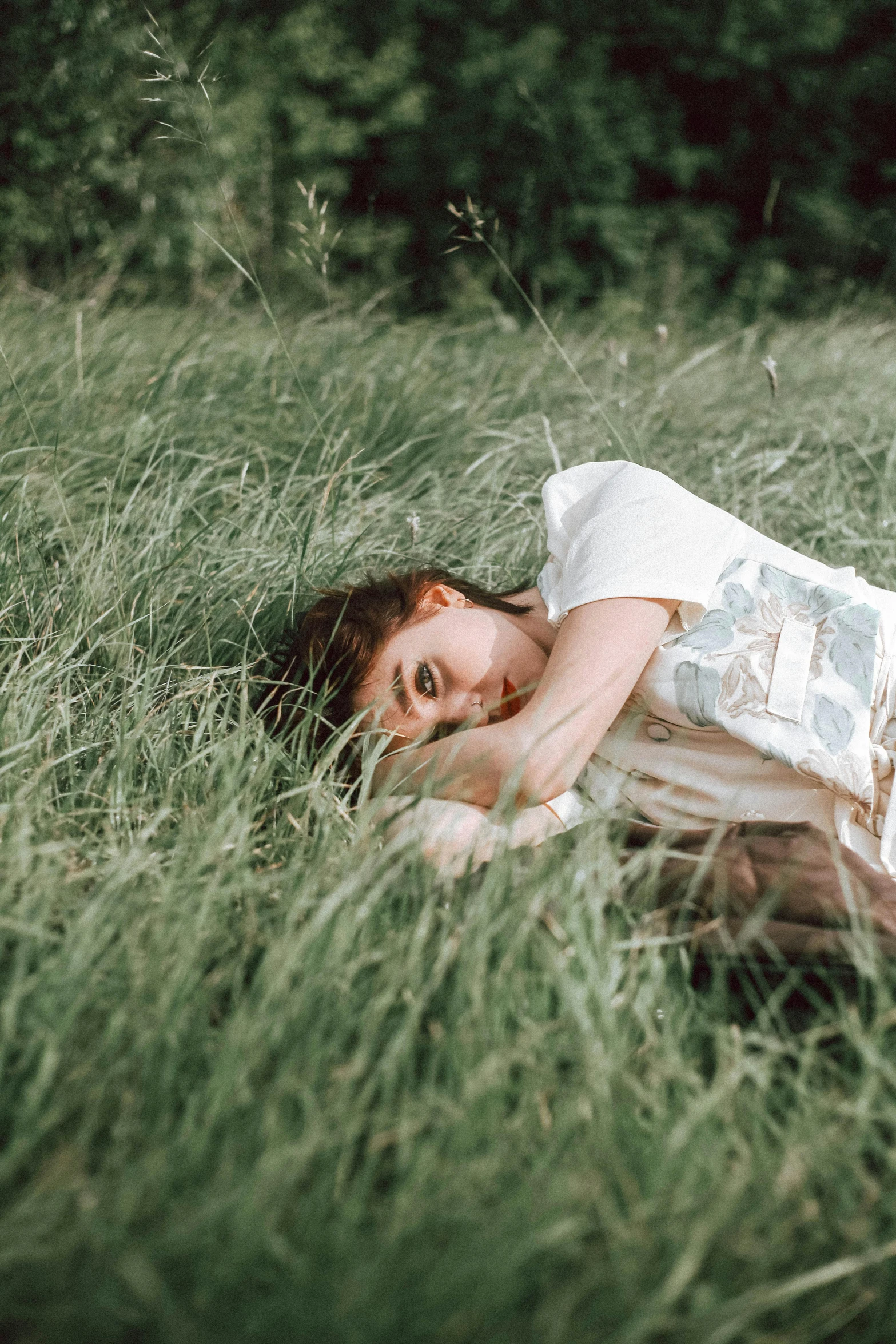 woman laying in grass with head between hands