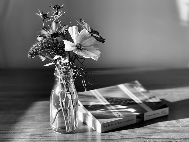 a clear vase with flowers in it next to some books