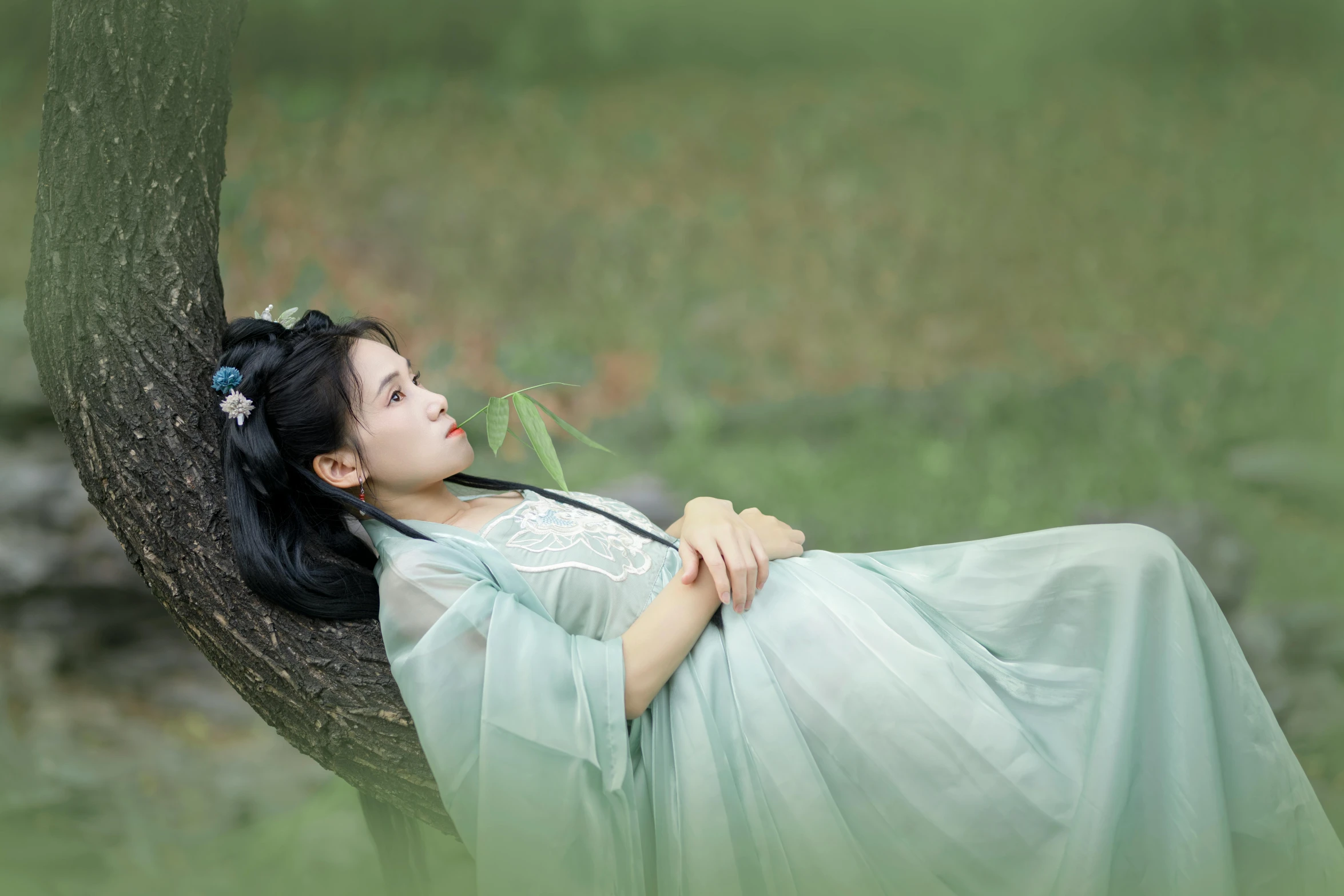 a woman in a green dress laying in a tree