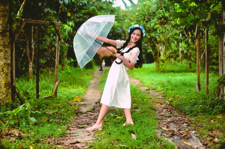 a woman in a white dress holds an umbrella and poses for a picture