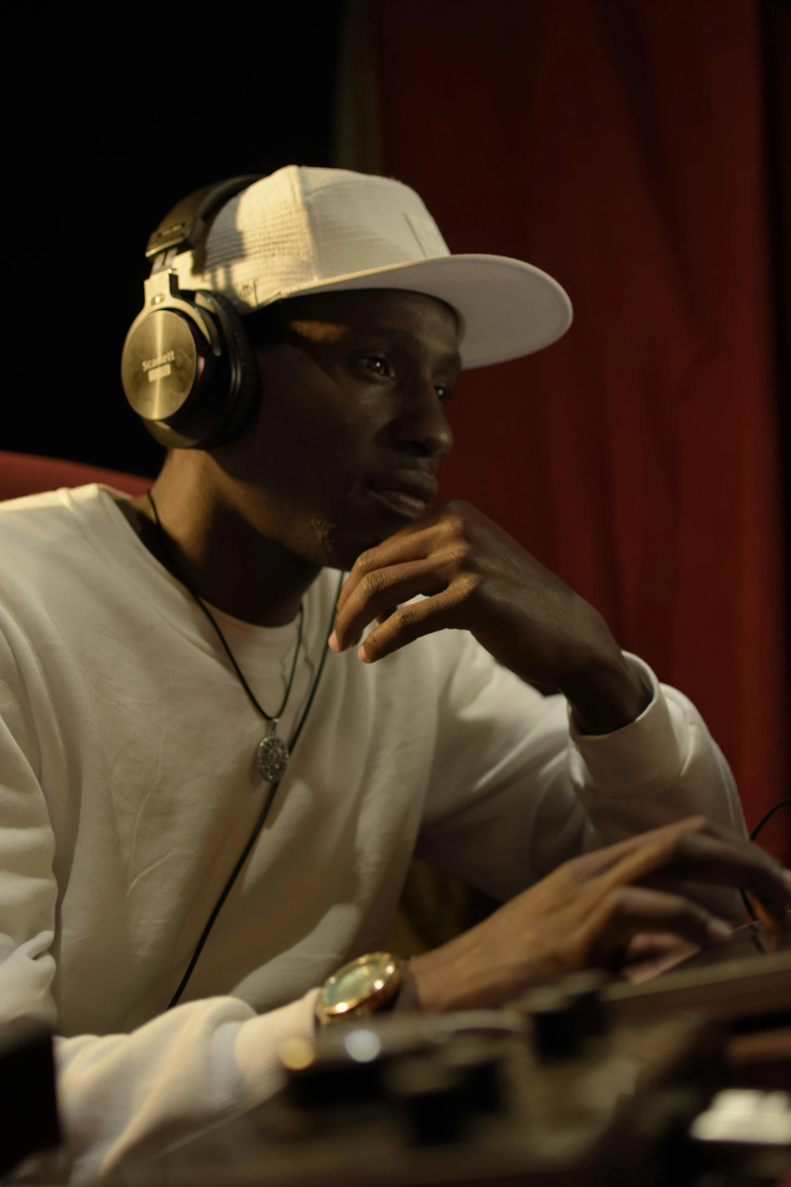 man with white cap listening to music on computer