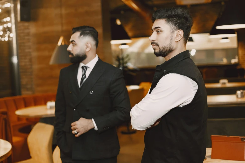 two well dressed men in formal attire standing at a counter