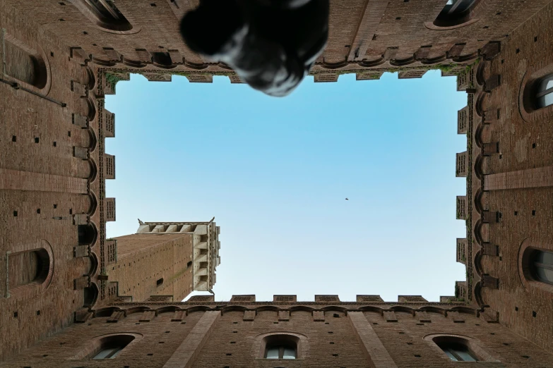 looking up at two large brick building structures, one with holes in the middle