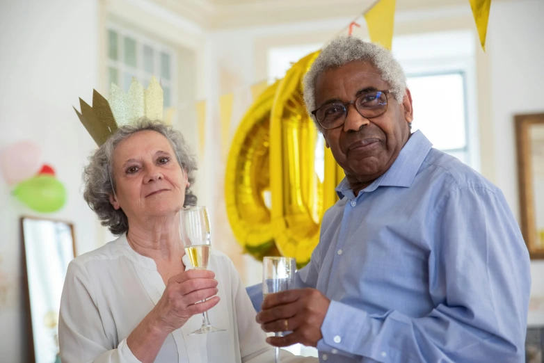 an old man and young lady with yellow balloon and a wine glass