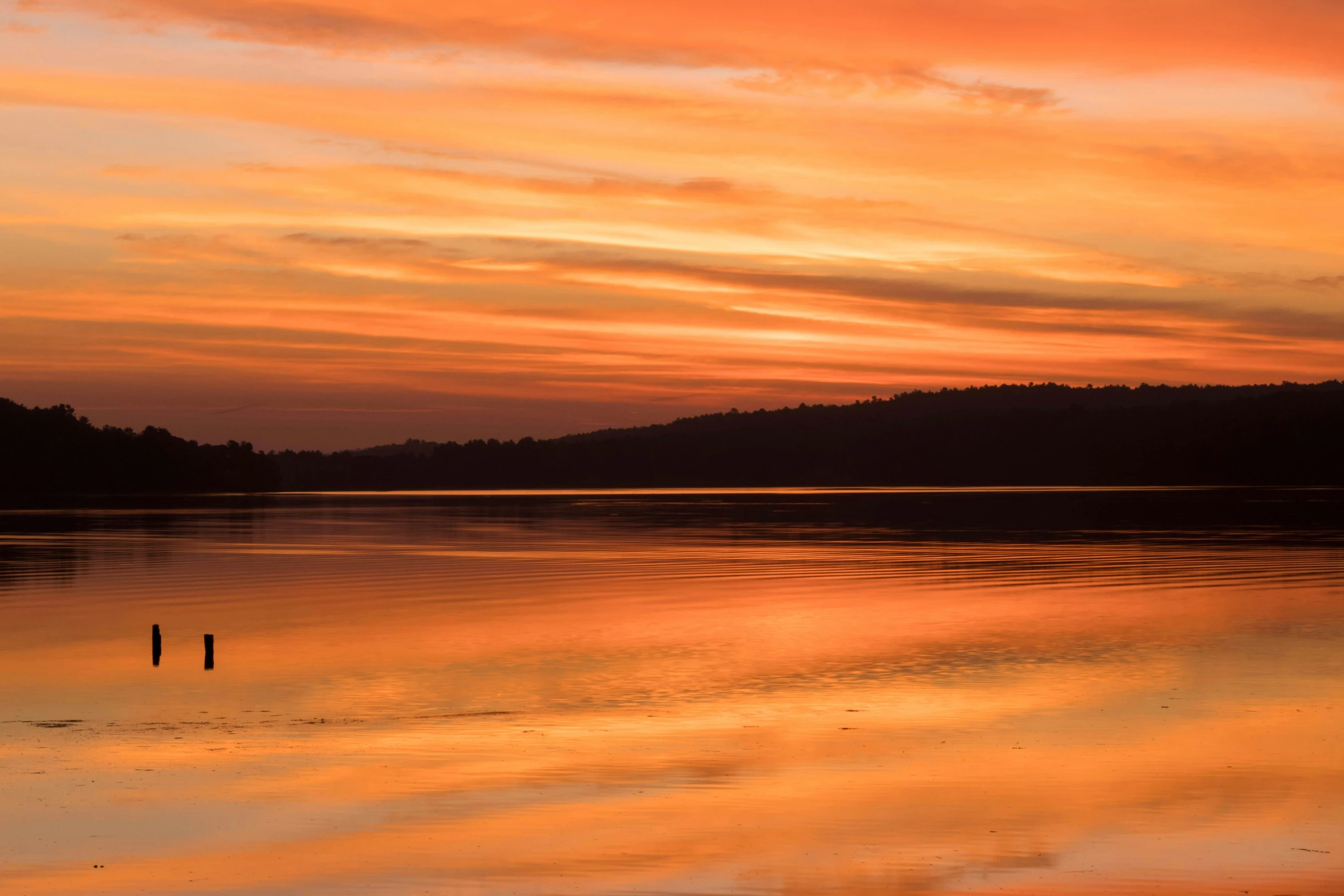 an orange and blue sky is reflected in the water