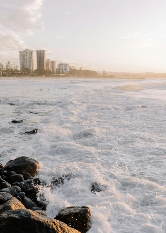 water is running over rocks with tall buildings in the background