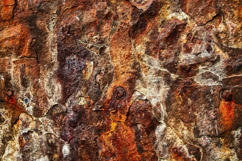 a brown rocky wall with different paint spots