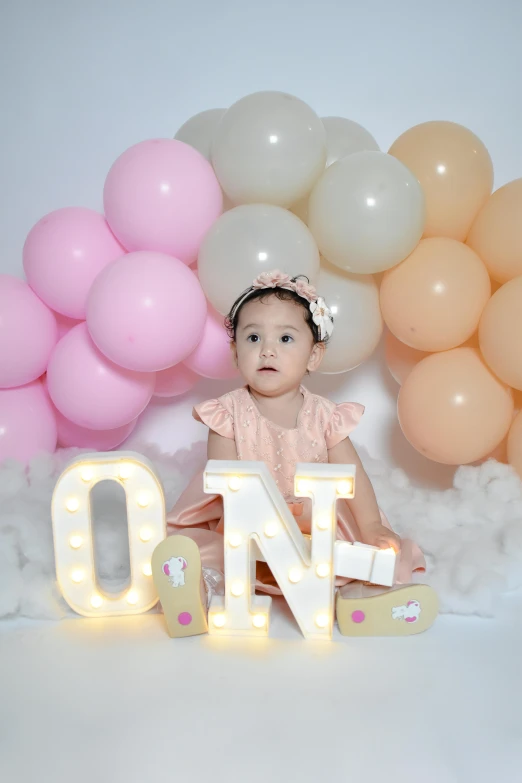 an adorable girl sitting next to a balloon letter