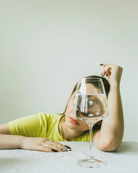 a woman sits on a table next to a glass of wine