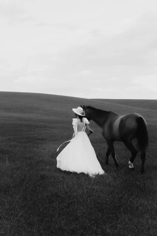 a woman in a dress and cowboy hat by a horse