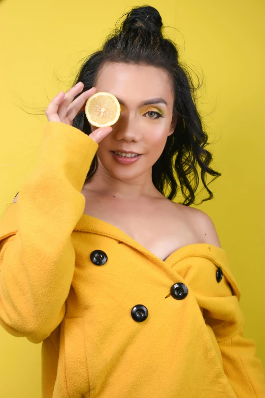 a young woman in yellow is holding a half - eaten lemon