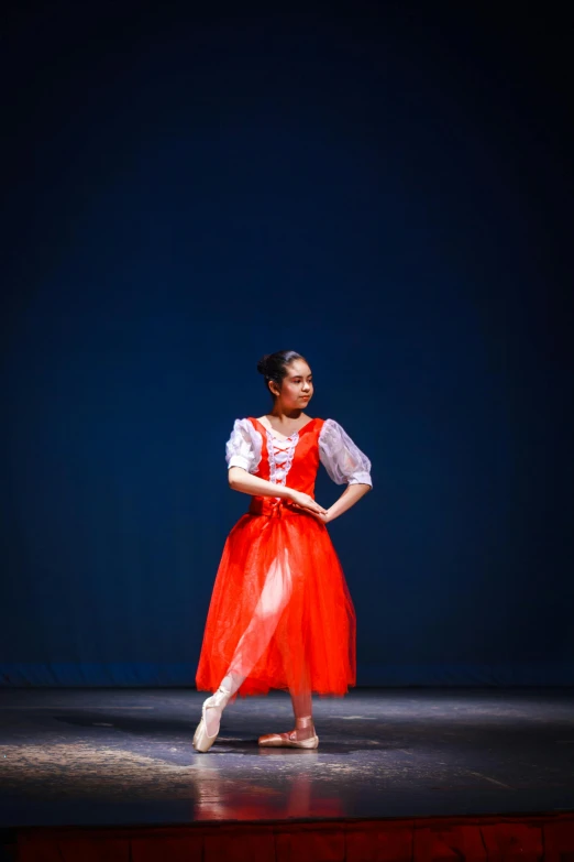 a ballet dancer standing on stage wearing red